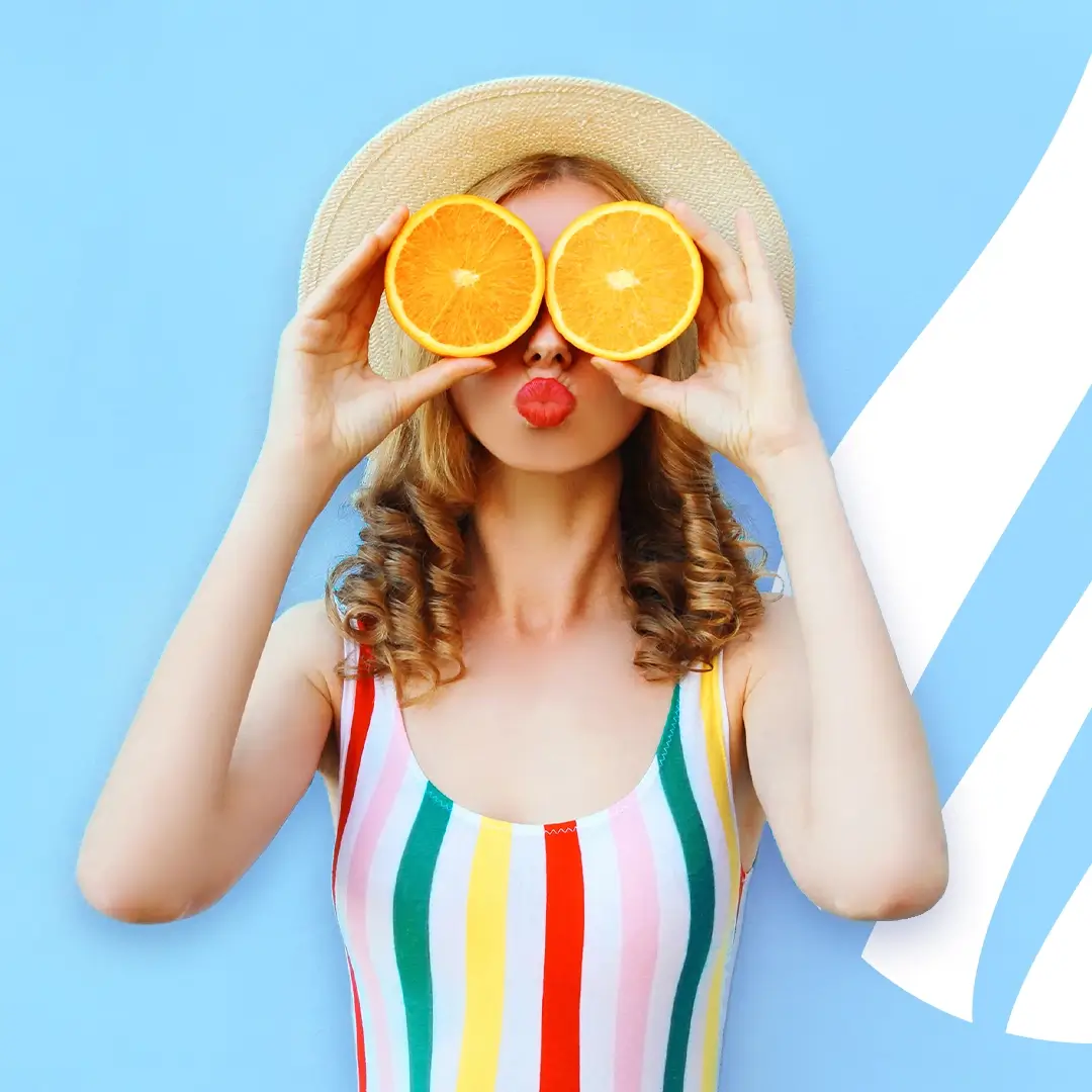 A beautiful woman holds orange slices in front of her eyes, radiating vibrancy and wellness, symbolizing the rejuvenating effects of IV therapy treatment at our Santa Rosa medical spa.